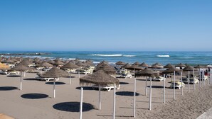 A beach with rows of thatched umbrellas and white lounge chairs. - Studio Apartment 'Estudio Bloque 89' with Sea View, Wi-Fi and Air Conditioning (Torrox)