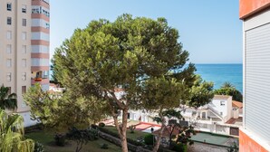 A residential area with a tree, a building with balconies, and a view of the sea. - Studio Apartment 'Estudio Bloque 84' with Sea View, Wi-Fi and Air Conditioning (Torrox)