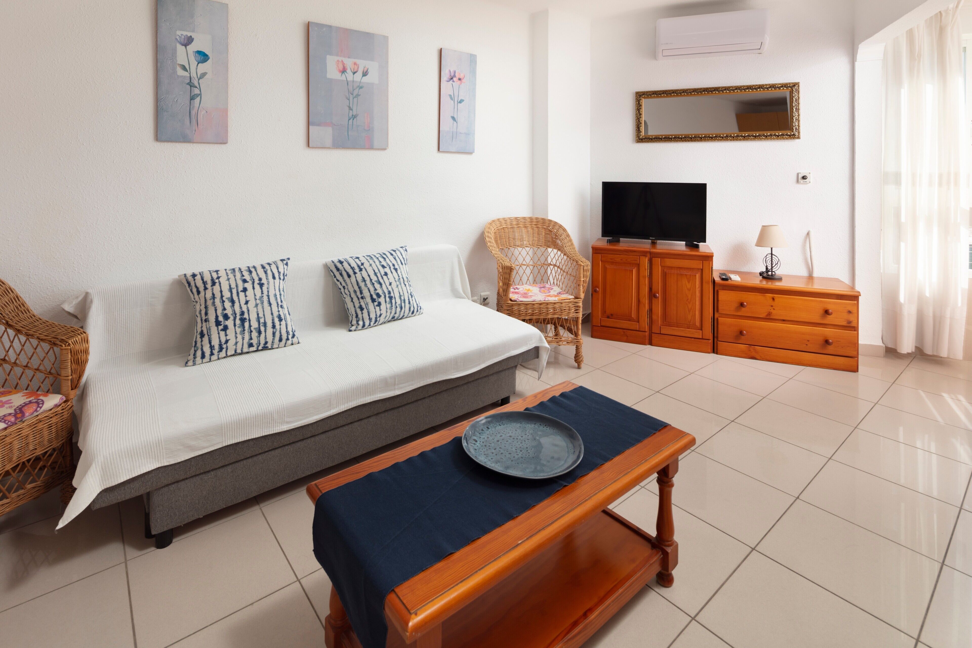 Un dormitorio con cama, televisor, cómoda y una silla.