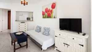 Un dormitorio con cama, televisor, cómoda, mesa y un cuadro de tulipanes.