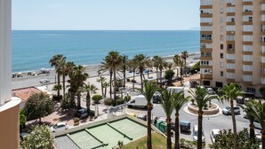 Un edificio alto con vista a la playa y palmeras.