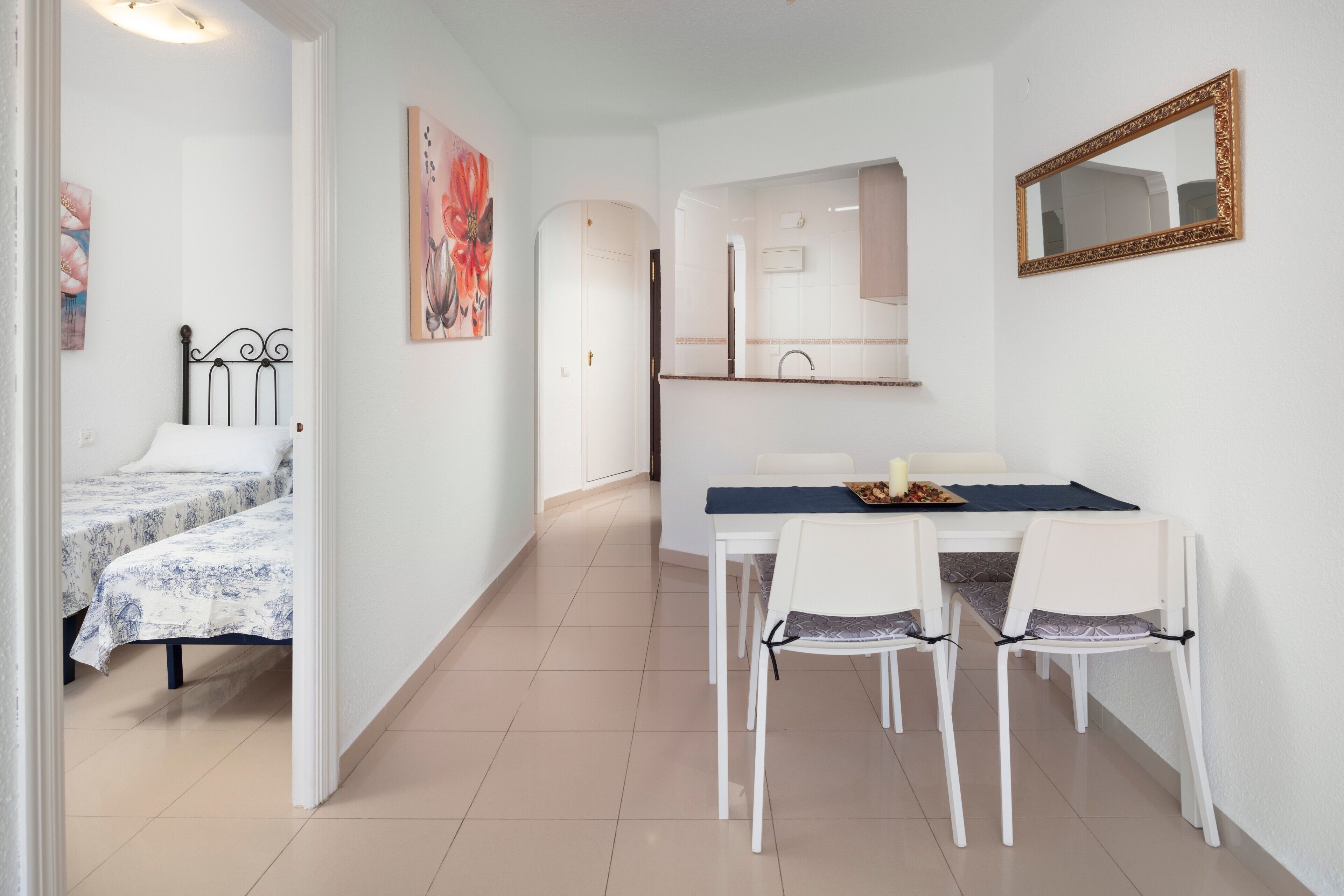 Una habitación con una cama, una mesa de comedor con sillas, un espejo y obras de arte en las paredes.