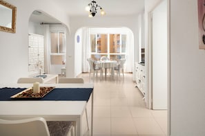 A modern kitchen with white cabinets, a dining area with a round table and chairs, and a view through a large window. - Apartment 'Bloque 78' with Sea View, Shared Pool and Wi-Fi (Torrox)