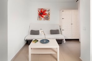 A white sofa with two grey cushions, a white coffee table with a book and a vase, and a white wardrobe with a door. - Apartment 'Bloque 78' with Sea View, Shared Pool and Wi-Fi (Torrox)
