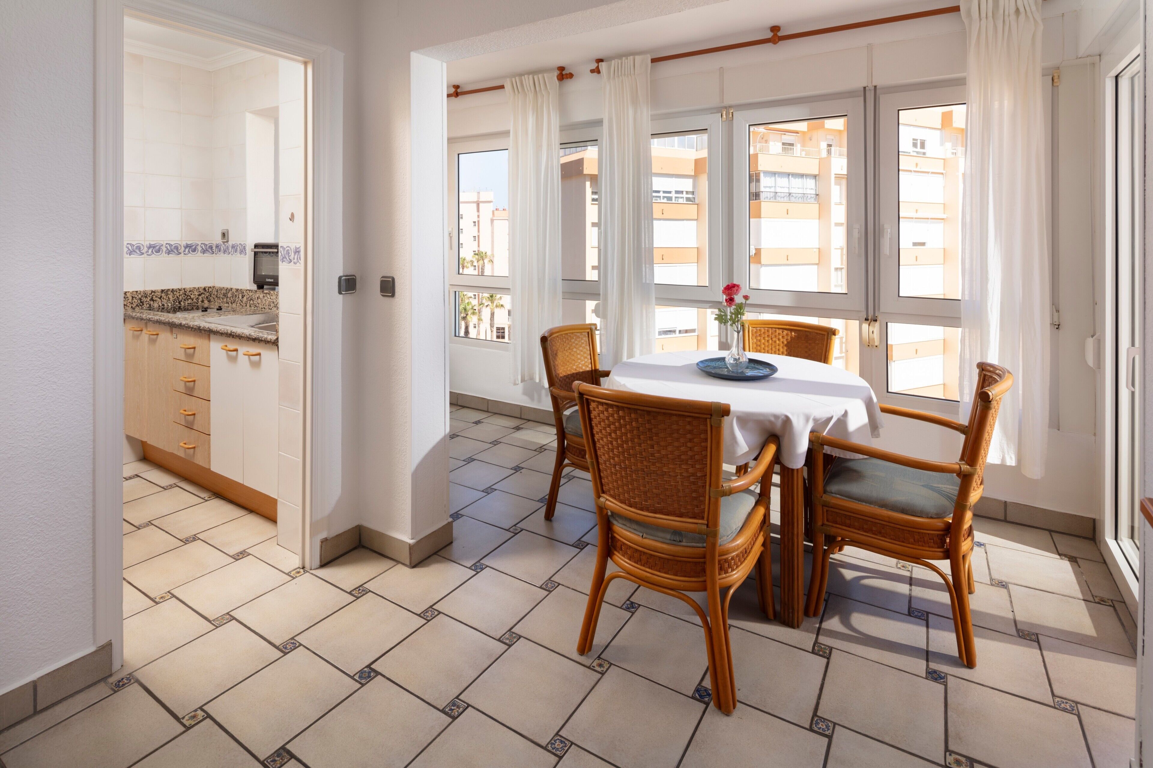 A dining area with a table, chairs, and a view of the city through large windows.