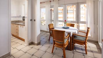A dining area with a table, chairs, and a view of the city through large windows.