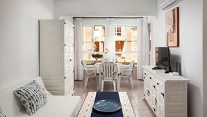 A room with a sofa, a dining table with chairs, a cabinet, and a TV. - Studio Apartment 'Estudio Bloque 90' with Sea View, Wi-Fi and Air Conditioning (Torrox)