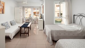 A bedroom with two beds, a desk, a chair, a sofa, and a window with curtains. - Studio Apartment 'Estudio Bloque 90' with Sea View, Wi-Fi and Air Conditioning (Torrox)