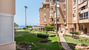 A multi-story building with balconies, a well-maintained lawn, and a clear view of the ocean. - Studio Apartment 'Estudio Bloque 90' with Sea View, Wi-Fi and Air Conditioning (Torrox)