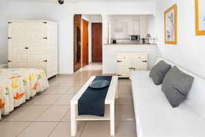 A room with a bed, a white sofa, a small table, a kitchen area, and a wardrobe. - Apartment 'Estudio 03 -09' with Sea View, Wi-Fi and Air Conditioning (Torrox)