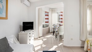 Un dormitorio con cama, televisión, cómoda y ventana con cortinas.
