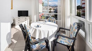 Un balcón con mesa, sillas, televisor y vistas panorámicas de la ciudad.