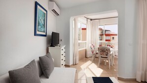 A hotel room with a bed, a TV, a desk, and a balcony with a table and chairs. - Studio Apartment 'Estudio 08 - 09' with Sea View, Wi-Fi and Air Conditioning (Torrox)