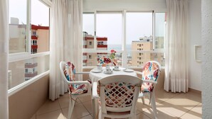 A balcony with a table set for two, chairs with floral patterns, and a view of buildings across the street. - Studio Apartment 'Estudio 08 - 09' with Sea View, Wi-Fi and Air Conditioning (Torrox)