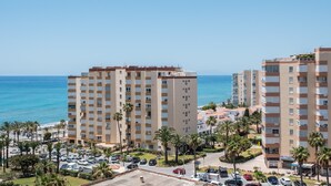 Un hôtel situé sur la côte, avec plusieurs étages, un parking et des palmiers.