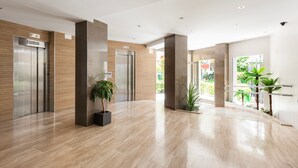 A modern lobby with two elevators, a wooden wall, a marble floor, and potted plants. - Studio Apartment 'Estudio 03-10' with Sea View, Wi-Fi and Air Conditioning (Torrox)