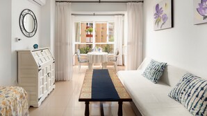 A room with a white sofa, a small table with a blue runner, a white cabinet, and a view of an outdoor patio with a table and chairs. - Studio Apartment 'Estudio 03-10' with Sea View, Wi-Fi and Air Conditioning (Torrox)