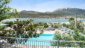 A pool area with lounge chairs and umbrellas, a view of the sea and mountains, and a clear sky. - Holiday Home 'Chakalaka - Villa 1' with Sea View, Wi-Fi and Air Conditioning (Leykada)