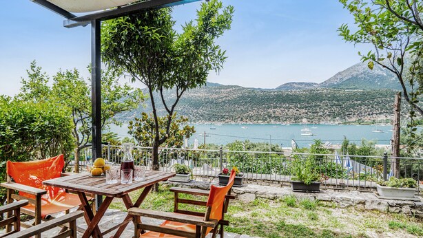 An outdoor patio with a table and chairs, overlooking a body of water and mountains. - Holiday Home 'Chakalaka - Villa 1' with Sea View, Wi-Fi and Air Conditioning (Leykada)