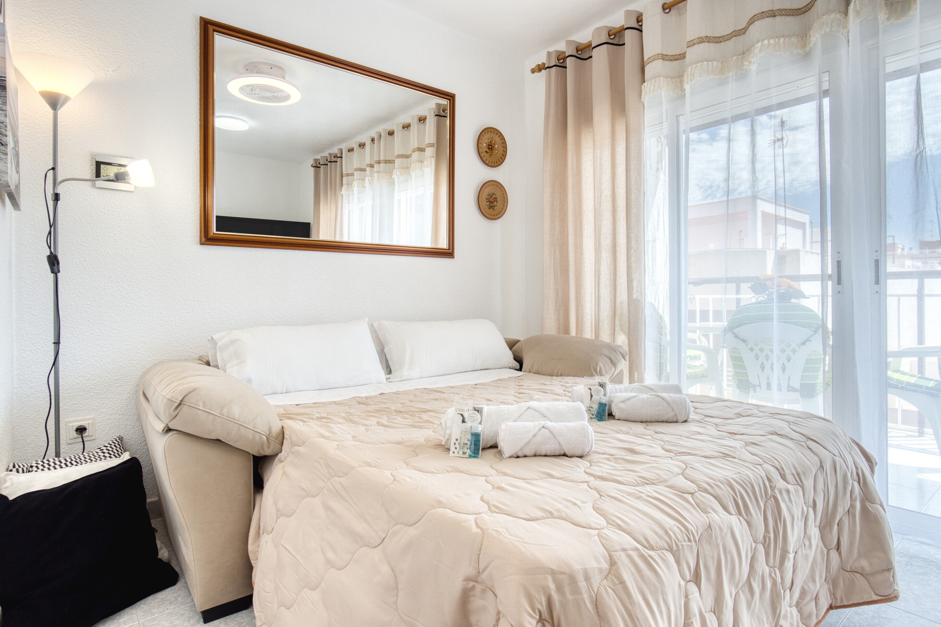 Une chambre d’hôtel avec un lit, un grand miroir, une fenêtre avec des rideaux et une vue sur l’extérieur.