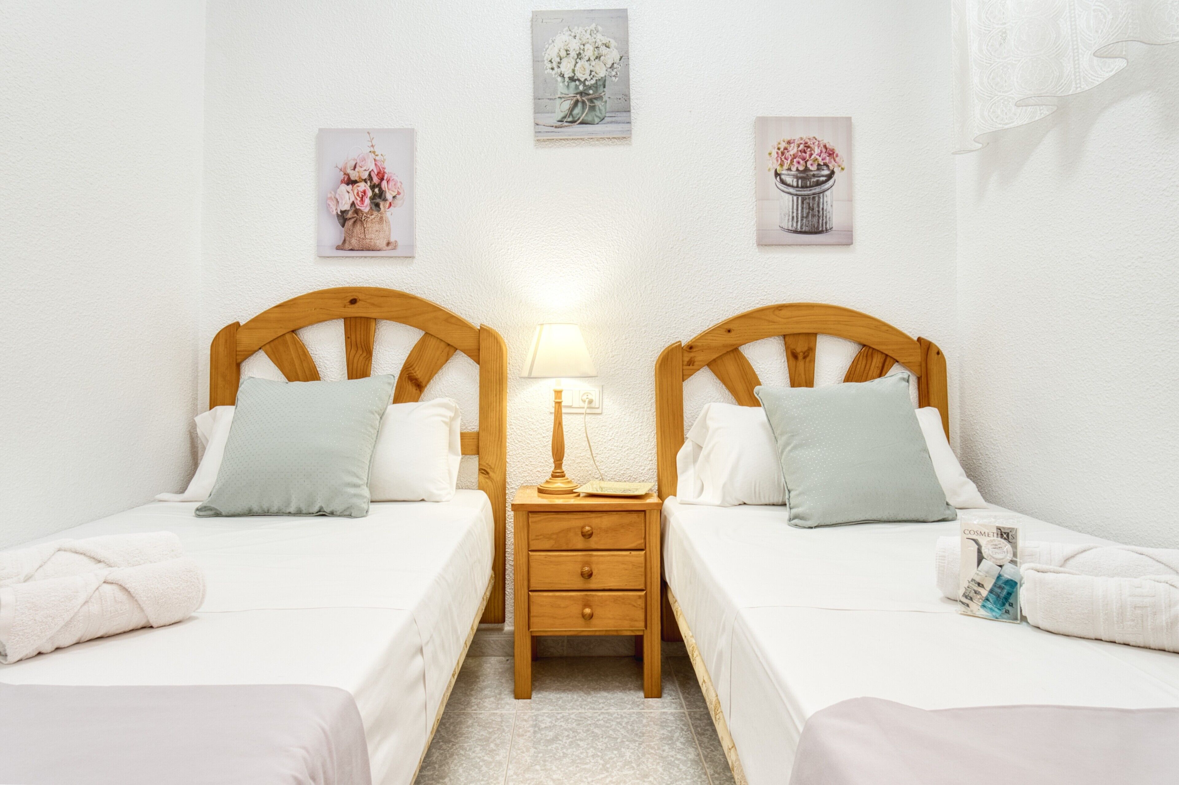 Habitación doble con dos camas, una mesita de noche con lámpara y una obra de arte en la pared.
