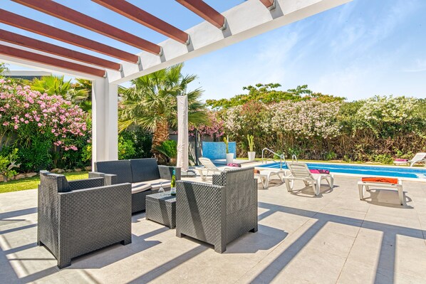 An outdoor patio with wicker furniture, a pool, and lush greenery. - Chalet 'Senna' with Mountain View, Wi-Fi and Air Conditioning (JAVEA)