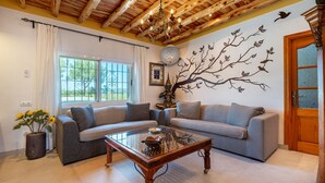 Un salon comprenant un canapé, une table basse en verre, une plante en pot et une fresque murale décorative.
