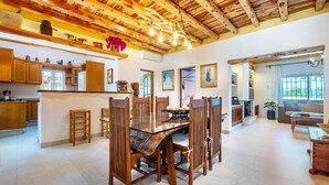 Un vaste espace de vie doté d’un plafond en bois, d’une table à manger en verre et de chaises en bois.