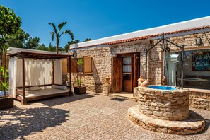 Un bâtiment en pierre doté d’un patio carrelé, d’une pergola en bois, d’une petite piscine et d’une porte en bois.