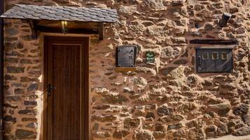 Un edificio de piedra con puerta de madera, una ventana pequeña y un cartel en la pared.