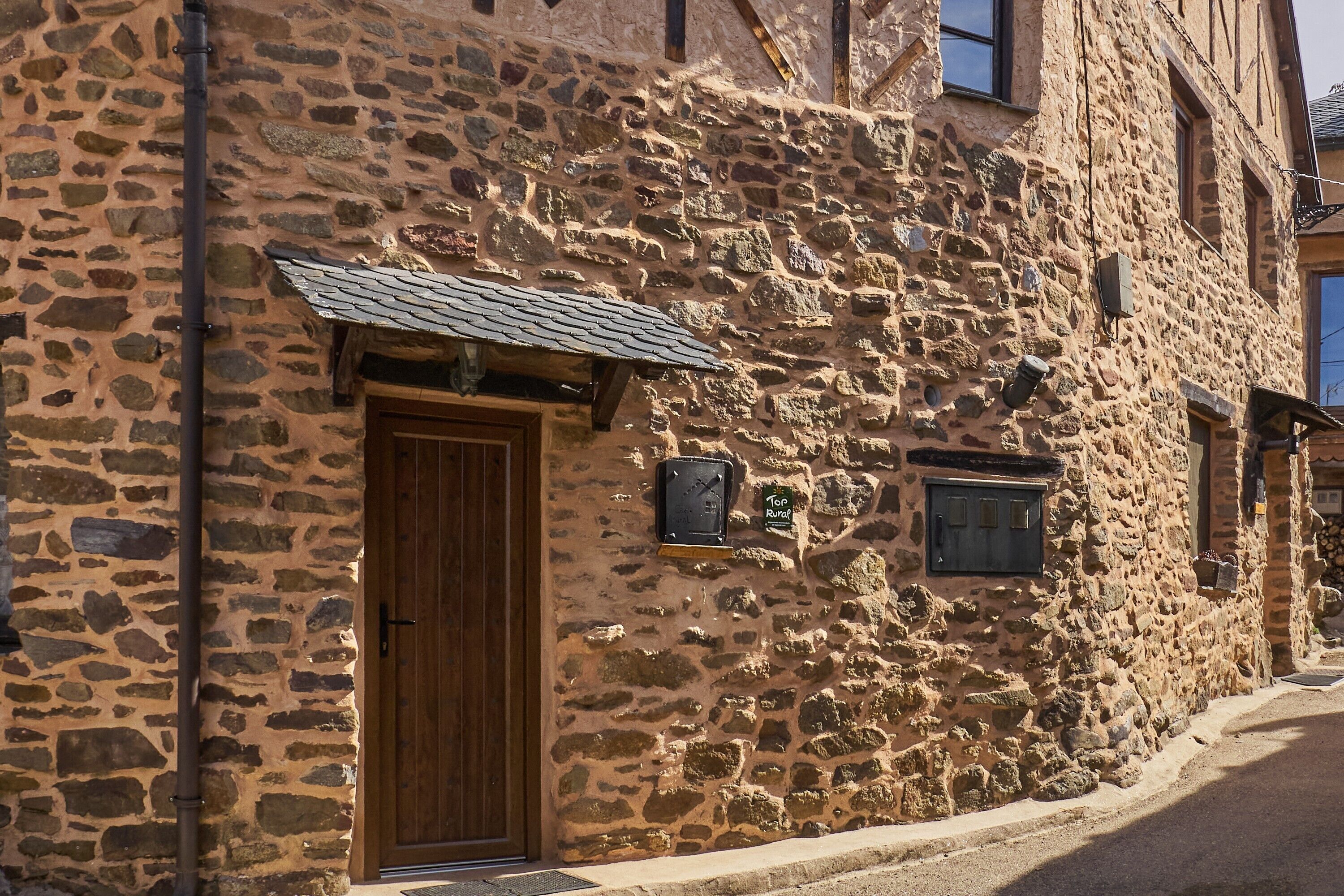 A stone building with a wooden door, a small window, and a mailbox.