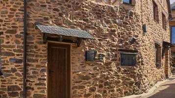 A stone building with a wooden door, a small window, and a mailbox.