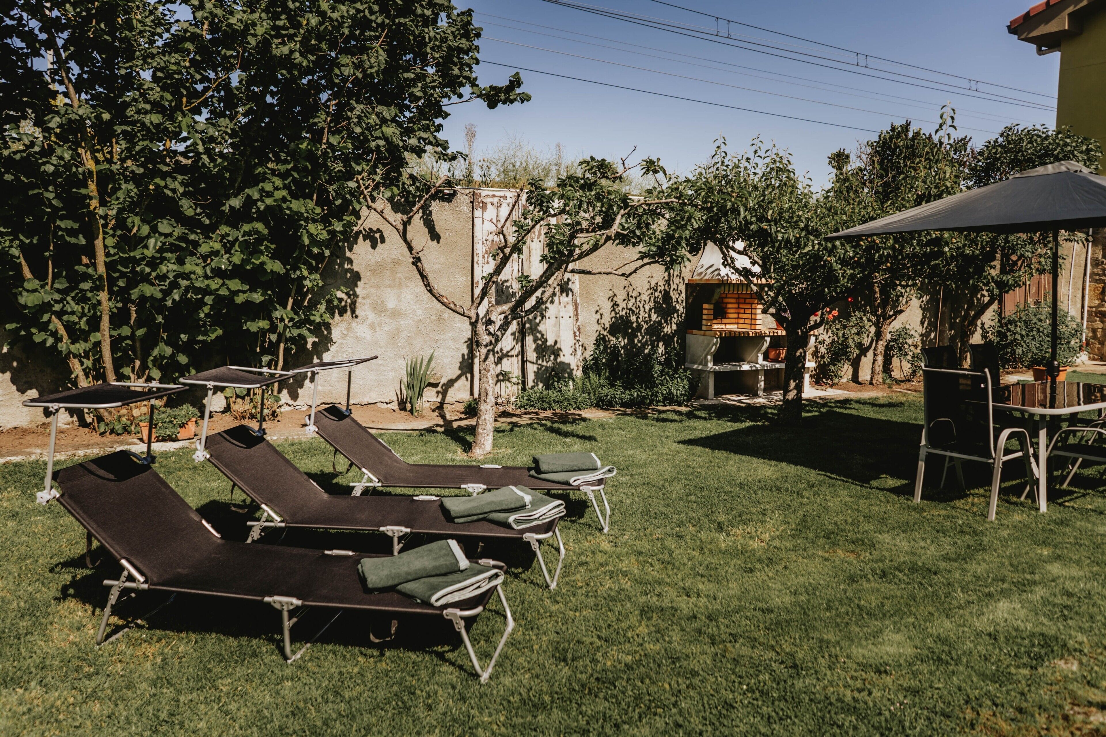 A patio with sun loungers, a grill, and a shaded area.