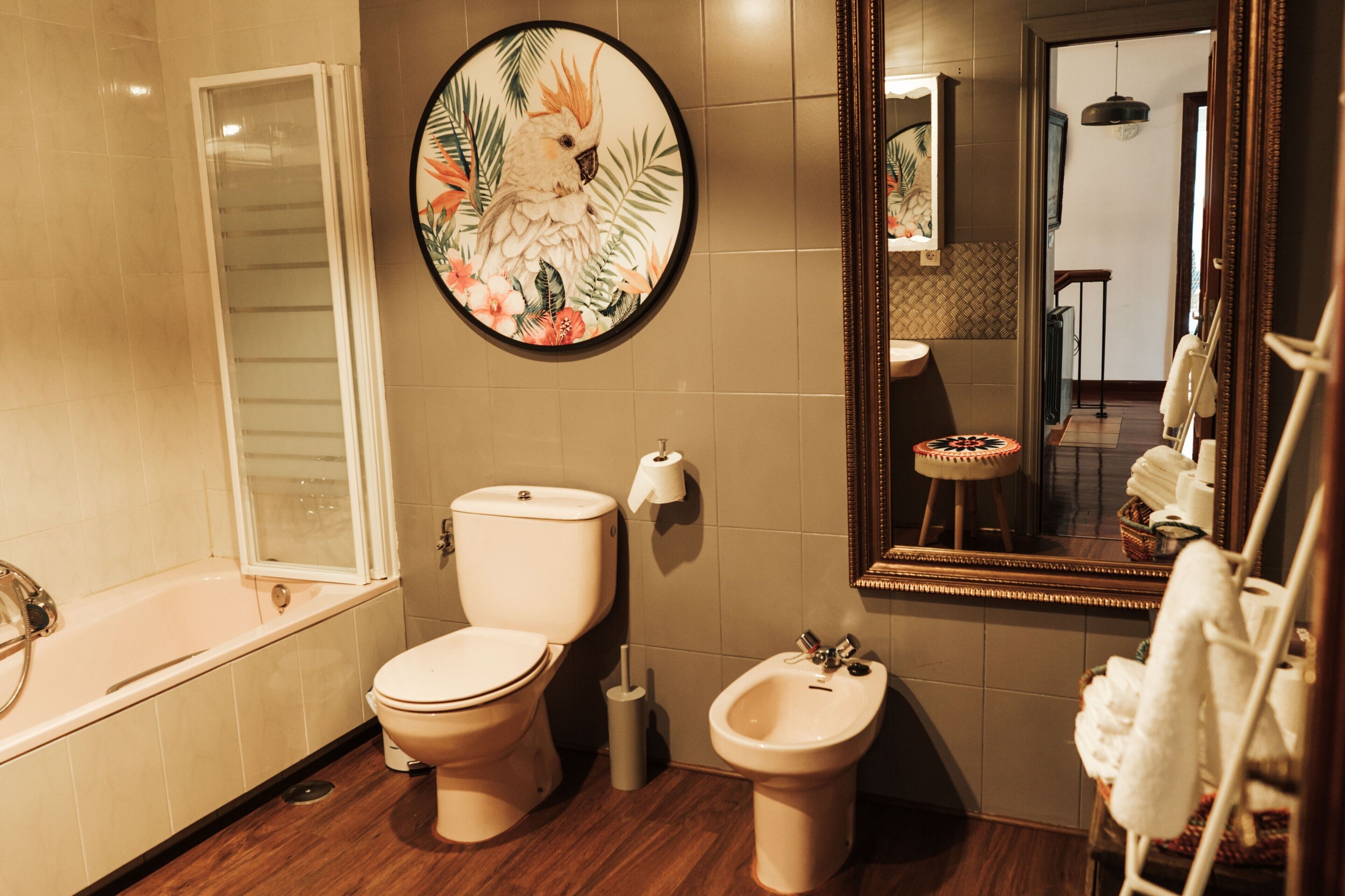 Une salle de bain équipée de toilettes, d’un bidet, d’une baignoire et d’un grand miroir.