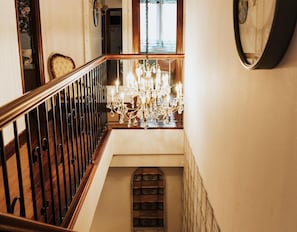 Un escalier avec une rampe en bois, un lustre et un mur orné de motifs.