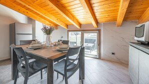 Une cuisine moderne avec des poutres en bois, une table à manger dressée avec des assiettes, des verres et un vase rempli de fleurs.