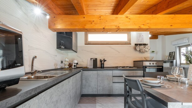 Une cuisine moderne équipée d’un four encastré, d’un évier et d’un coin repas avec une table mise pour deux personnes.