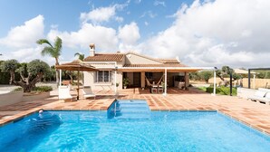 A swimming pool with a tiled deck, a covered patio area, and a building with a tiled roof. - Villa 'Tranquila El Retiro' with Private Pool, Wi-Fi and Air Conditioning (Málaga)