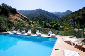 Une piscine avec des chaises longues et une vue sur les montagnes.