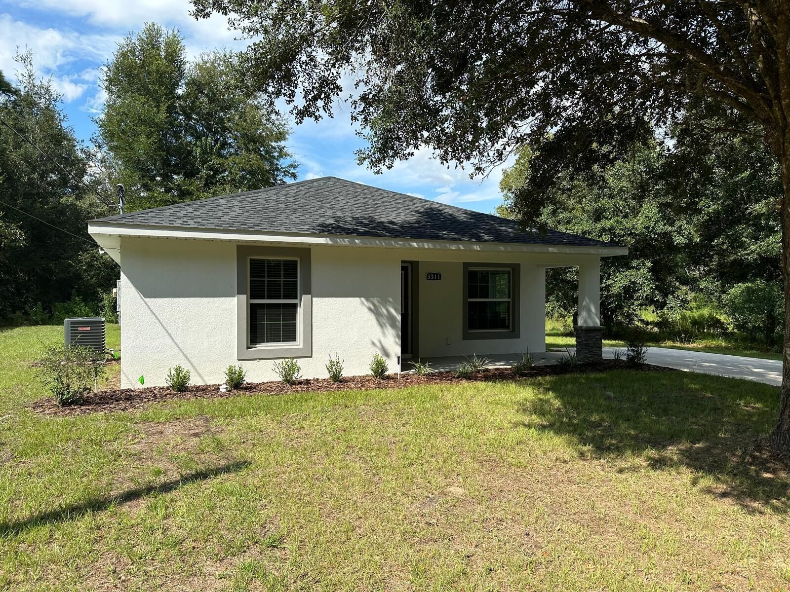 A small, single-story house with a white exterior and a dark roof.