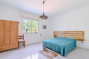 A bedroom with a bed, wooden wardrobe, chair, window, and a hanging light fixture. - Holiday Home 'Villa Ottavia' with Private Terrace, Wi-Fi and Air Conditioning (Torre Lapillo)
