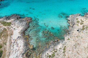 An aerial view of a coastal area with clear turquoise waters, rocky terrain, and sparse vegetation. - Holiday Home 'Villa Ottavia' with Private Terrace, Wi-Fi and Air Conditioning (Torre Lapillo)
