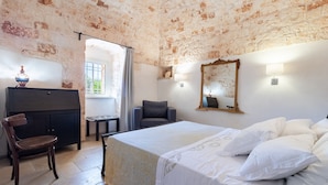 Ein Zimmer mit Bett, Stuhl, Schreibtisch, Lampe und Spiegel.