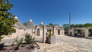 Ein Innenhof mit Steingebäuden, einer Pergola und Gartenmöbeln.
