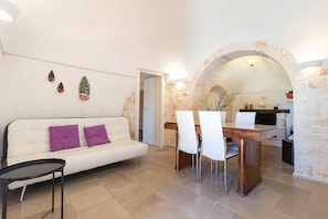 Ein modernes Interieur mit einem weißen Sofa, einem Esstisch mit Stühlen und einem Steingewölbe.