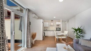 A modern kitchen with white cabinets, a dining area with a white table and chairs, and a grey sofa. - Vacation Apartment 'Beach Holidays' with Shared Pool, Wi-Fi and Air Conditioning (Adeje)