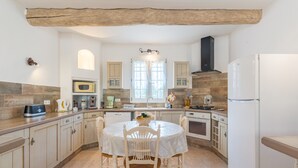 A kitchen with a round table, white cabinets, a built-in oven, and a refrigerator. - Holiday Home 'Mas Provençal' with Private Pool, Wi-Fi and Air Conditioning (Saint-Rémy-de-Provence)