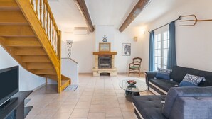 A living room with a wooden staircase, a fireplace, a sofa, and a television. - Holiday Home 'Mas Provençal' with Private Pool, Wi-Fi and Air Conditioning (Saint-Rémy-de-Provence)