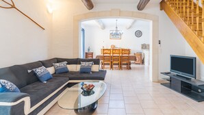 A living room with a sofa, coffee table, TV, and a staircase. - Holiday Home 'Mas Provençal' with Private Pool, Wi-Fi and Air Conditioning (Saint-Rémy-de-Provence)