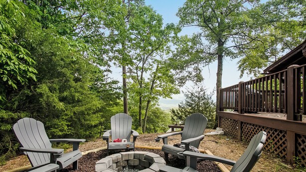 A deck with Adirondack chairs and a fire pit surrounded by trees. - NEW!! Mountain Views! Quiet Escape w/ Fire Pit, Hot Tub, Front Porch Sitting (Sevierville)